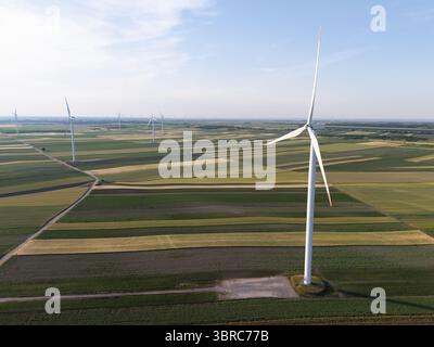 Vue aérienne des éoliennes sur un champ agricole au coucher du soleil. Banque D'Images