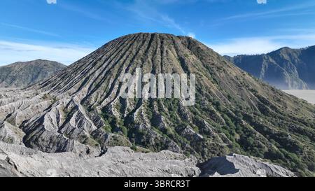 Une vue spectaculaire d'un cône volcanique avec de profondes crêtes verticales sculptées par l'érosion, debout fièrement sous un ciel bleu clair. L'art de la nature est plein Banque D'Images