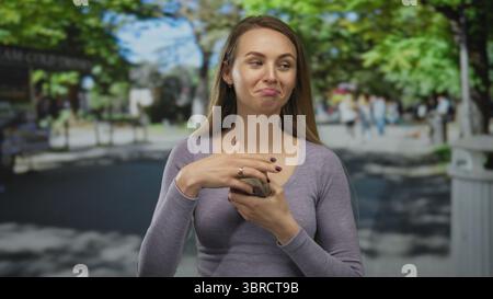 Femme tenant des billets de banque zloty polonais dans une rue de la ville, entourée de paysages extérieurs, communique un sentiment d'assurance financière et de lif urbain décontracté Banque D'Images