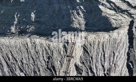 Une vue aérienne à couper le souffle capture une ligne de visiteurs montant l'escalier spectaculaire creusé dans le bord abrupt d'un cratère volcanique actif. Banque D'Images