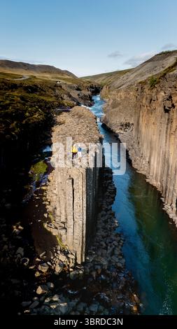 Deux randonneurs explorent les paysages époustouflants du canyon Studlagil en Islande, entourés d’imposantes colonnes de basalte et d’eaux scintillantes. Cette aventure en plein air met en valeur la beauté naturelle islandaise. Banque D'Images