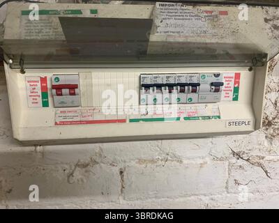 Vieux câblage électrique unité de distribution de gaz tuyaux fils câbles sales Dingy installés sur le mur dans un compteur de cave gaz électricité cadre en bois électrique UK Banque D'Images