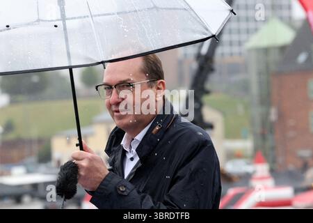 Rostock, Allemagne. 12 juillet 2025. Alexander Dobrindt (CSU), ministre fédéral de l'intérieur, sous un parapluie lors de la conférence de presse d'ouverture de la Journée nationale de la protection civile dans le port de la ville hanséatique. Environ 40 acteurs des secteurs de l’incendie, de la protection civile et de la lutte contre les catastrophes fournissent des informations sur leur travail. Rostock est la troisième ville après Potsdam et Wiesbaden à accueillir la journée, qui a cette fois pour devise « L'eau - utiliser les ressources, maîtriser les risques ». Crédit : Bernd Wüstneck/dpa/Alamy Live News Banque D'Images