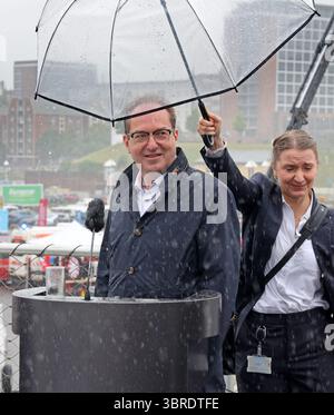 Rostock, Allemagne. 12 juillet 2025. Alexander Dobrindt (CSU), ministre fédéral de l'intérieur, sous un parapluie lors de la conférence de presse d'ouverture de la Journée nationale de la protection civile dans le port de la ville hanséatique. Environ 40 acteurs des secteurs de l’incendie, de la protection civile et de la lutte contre les catastrophes fournissent des informations sur leur travail. Rostock est la troisième ville après Potsdam et Wiesbaden à accueillir la journée, qui a cette fois pour devise « L'eau - utiliser les ressources, maîtriser les risques ». Crédit : Bernd Wüstneck/dpa/Alamy Live News Banque D'Images