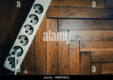 Distributeur de puissance pour prises, vue de dessus, parquet ancien en arrière-plan. Banque D'Images