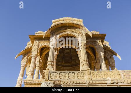 Vue de sculptures en grès doré d'un chhatri historique s'élevant contre le ciel bleu clair, une merveille architecturale de conception complexe, Jaisalmer, Rajasthan, Inde. Banque D'Images