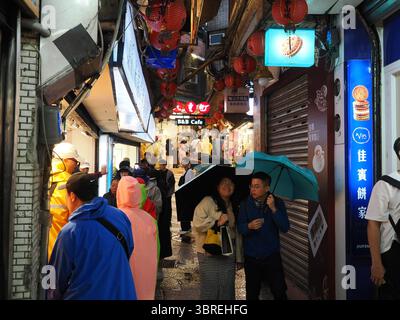 Jiufen, Taiwan - 8 novembre 2024 - les touristes avec des parapluies remplissent une ruelle étroite ornée de lanternes sur la vieille rue Jiufen, naviguant dans la boutique animée Banque D'Images