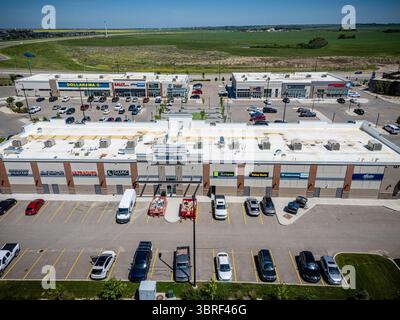 Grand centre commercial avec beaucoup de places de parking. Le centre commercial est rempli de voitures et de camions, et il y a plusieurs personnes qui se promènent. Le ciel est cle Banque D'Images