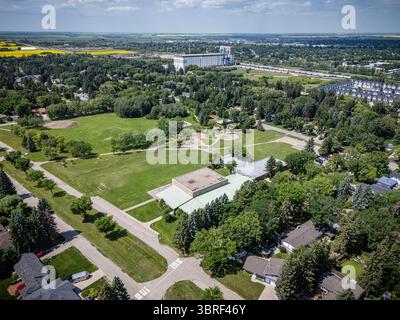 Vue d'un quartier résidentiel avec un grand bâtiment en arrière-plan. Les maisons sont pour la plupart vertes et l'herbe est luxuriante Banque D'Images