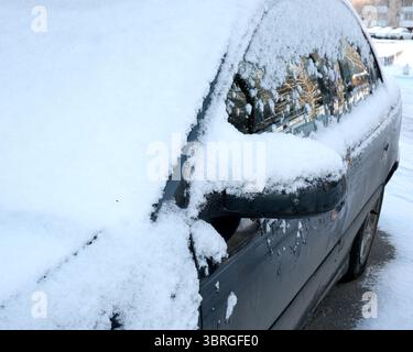 Une voiture garée est recouverte d'épaisses couches de neige un jour d'hiver. Banque D'Images