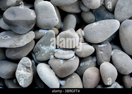 Diverses pierres arrondies brillent doucement, mélangées avec un soupçon de sel. Banque D'Images