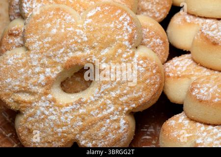 Les petits gâteaux en forme de fleur terreuse fraîchement cuits sont ornés d'un léger saupoudrage de sucre, invitant les clients à se livrer à une friandise sucrée lors d'un afte ensoleillé Banque D'Images