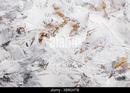 Pâte blanche mastic mélangée à de l'encre noire, détail abstrait gros plan des coups de spatule sur la rénovation de stuc de peinture dorée, Banque D'Images