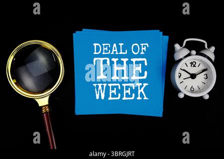 Texte de l'offre de la semaine sur note adhésive avec loupe et réveil sur fond noir Banque D'Images