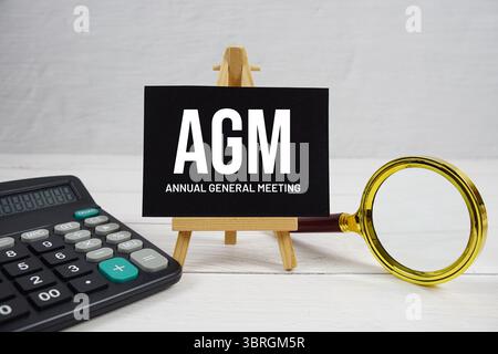 Abréviation de l'AGA du texte de l'Assemblée générale annuelle avec loupe et calculatrice sur fond de bois Banque D'Images