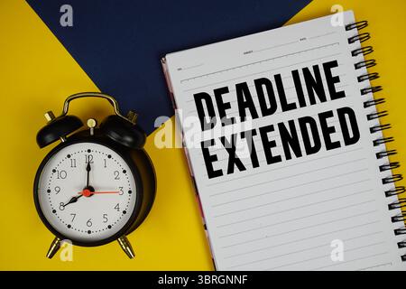 Date limite texte étendu écrit sur le bloc-notes avec réveil sur fond jaune Banque D'Images