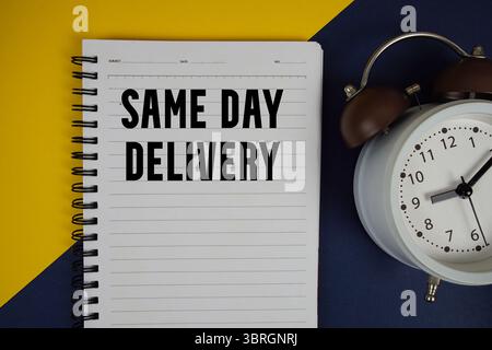 Le texte de livraison le jour même est écrit sur le bloc-notes avec le réveil sur fond jaune Banque D'Images