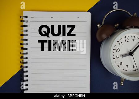 Texte de l'heure du quiz écrit sur le bloc-notes avec réveil sur fond jaune Banque D'Images