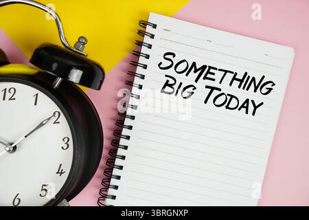Something Big Today texte écrit sur bloc-notes avec réveil sur fond rose Banque D'Images