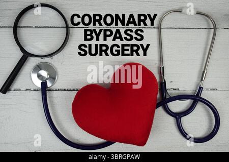 Texte de chirurgie coronaire de contournement avec cœur rouge, loupe et stéthoscope médical sur fond en bois Banque D'Images