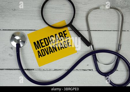 Texte Medicare Advantage avec loupe et stéthoscope médical sur fond en bois Banque D'Images