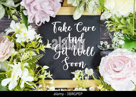 Prenez soin et obtenez bien bientôt le texte avec la décoration de bouquet de fleurs sur fond de bois Banque D'Images