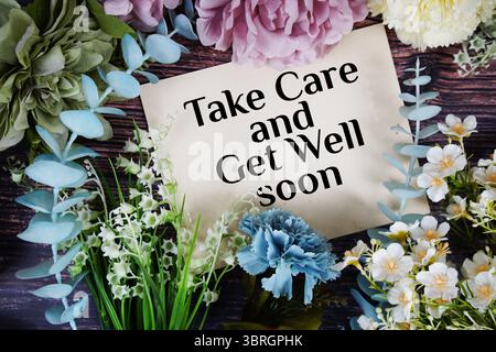 Prenez soin et obtenez bien bientôt le texte avec la décoration de bouquet de fleurs sur fond de bois Banque D'Images