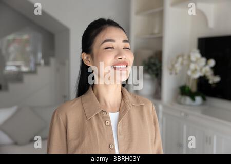 Jeune femme asiatique des années 30 souriant les yeux fermés Banque D'Images