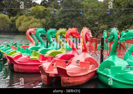 Bateaux à aubes rouges et verts amarrés sur le lac à Peasholm Park, Scarborough, avec des arbres et le rivage en arrière-plan. Pédalo ou pédalos. Banque D'Images