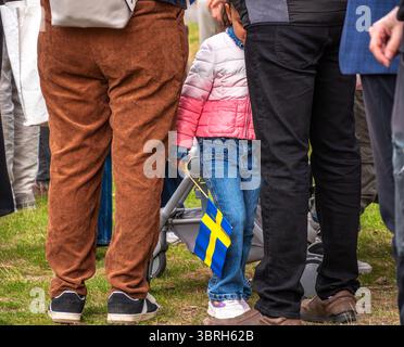 Sodertalje, Suède - 6 juin 2025 : un enfant tenant un petit drapeau suédois se tient parmi une foule de gens. La scène capture un moment de célébration ou Banque D'Images