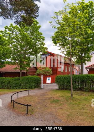 Sodertalje, Suède - 6 juin 2025 : une charmante maison en bois rouge entourée d'arbres verdoyants et d'un chemin de gravier. La scène se déroule dans un environnement serein Banque D'Images