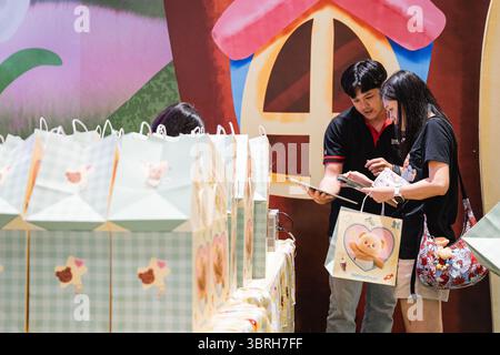 Bangkok, Thaïlande. 12 juillet 2025. Un membre du personnel confirme un achat de marchandise Butterbear chez Buttery World. Butterbear mania prend le contrôle de Siam Paragon à Bangkok alors que les fans se rassemblent autour de la mascotte virale thaïlandaise devenue idole d'Internet lors d'une apparition publique dans sa pâtisserie. Connue sous le nom de « Nong Noey », elle a évolué de mascotte de marque à icône de la culture pop, avec des couvertures de danse, des vidéos de réaction et des clips musicaux. Autrefois un succès parmi les touristes chinois, Butterbear charme maintenant les fans du monde entier. (Photo de Ploy Phutpheng/SOPA images/Sipa USA) crédit : Sipa USA/Alamy Live News Banque D'Images