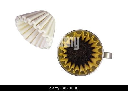 Vue de dessus de la pile de nouveaux filtres à café en papier jetables de type panier et de grains de café torréfiés moulus dans un filtre à café en papier dans un support de cône en métal isolé Banque D'Images