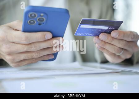 Homme asiatique payant avec carte de crédit sur téléphone intelligent au bureau. Homme utilisant smartphone pour acheter portefeuille électronique en ligne Banque D'Images