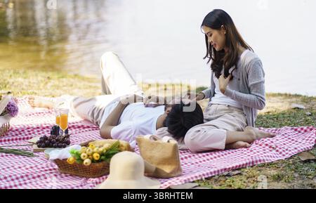 Heureux couple asiatique romantique couché à l'heure du pique-nique du parc dans les vacances d'été Banque D'Images