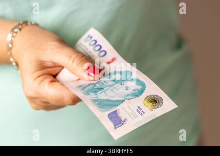 Argentine argent. Une femme tient un nouveau billet de 10 000 peso argentin dans sa main. Une grande dénomination. Concept financier et commercial Banque D'Images