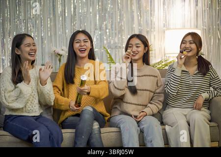 Amis joyeux appréciant la fête de vacances d'anniversaire à la maison. Amis asiatiques célébrant Noël ou fête du nouvel an Banque D'Images