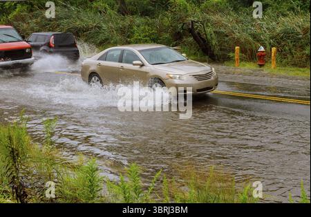 Les voitures qui circulent sur une route inondée pendant une inondation forte pluie Banque D'Images