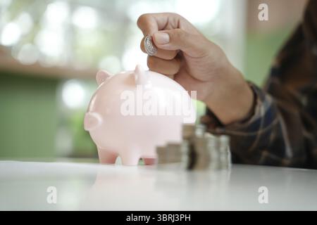 Économiser de l'argent. main mettre de l'argent dans la tirelire rose faisant des investissements ou de la stratégie pour l'épargne personnelle Banque D'Images