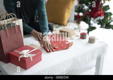 Homme en pull enveloppant cadeaux de noël avec éco Paper Girl emballage cadeaux de noël concept de vacances de noël Banque D'Images