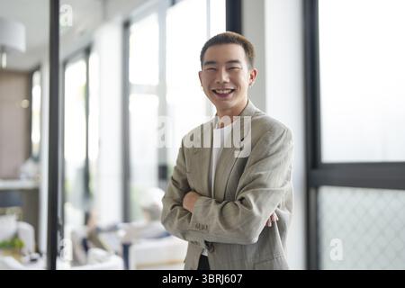 Souriant jeune homme d'affaires asiatique dans le bureau moderne. bel homme asiatique heureux et amical tout en travaillant le travail de succès Banque D'Images