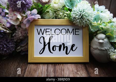 Texte de bienvenue à la maison avec décoration florale sur fond en bois Banque D'Images