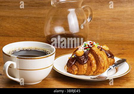 Croissant garni de chocolat et d'arc-en-ciel. Croissant français garni de chocolat et d'arc-en-ciel saupoudrés dans un plat en céramique brun avec un Banque D'Images