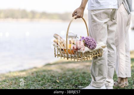 Couple marchant dans le jardin avec panier pique-nique. en couple amoureux profite du temps de pique-nique dans le parc en plein air Banque D'Images