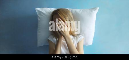 Contrarié triste femme pleurant couvrant ses yeux avec ses mains couchées sur l'oreiller tout en éprouvant l'insomnie ou la souffrance mentale à la maison Banque D'Images