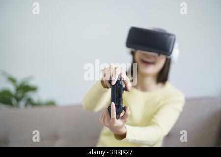 Jeune femme asiatique portant la réalité virtuelle touchant l'air pendant le concept de technologie future de l'expérience VR Banque D'Images