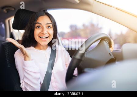 Femme indienne surprise et joyeuse à l'intérieur de la voiture avec les mains levées dans l'amusement Banque D'Images