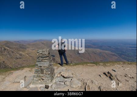 Femme randonneur regardant depuis le sommet du vieil homme de Coniston dans le Lake District Banque D'Images
