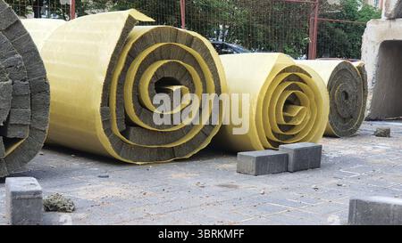 Rouleaux de matériau d'isolation thermique reposant sur la chaussée d'un chantier de construction Banque D'Images