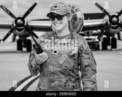 L. Col. Leone de l'US Air Force au salon aérien McGuire AFB, le 16 mai 2025, en uniforme avec radio en main et avions vintage derrière. Banque D'Images